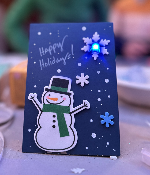 Teknikio blue LED light holiday card featuring a snowman and foam snowflakes